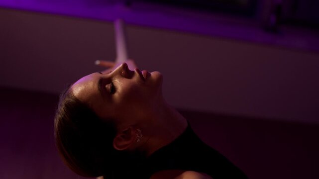 Graceful athletic dancer performing a sensual high heels routine in a dimly lit studio
