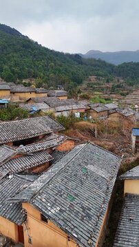 Vertical Video: Layered grey tile roofs and yellow mud walls of traditional ethnic village homes