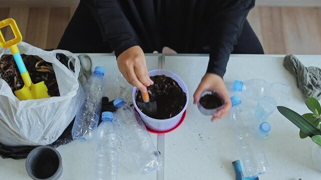 ASMR gardening video of filling plastic bottle cut-out with soil using small trowel for planting