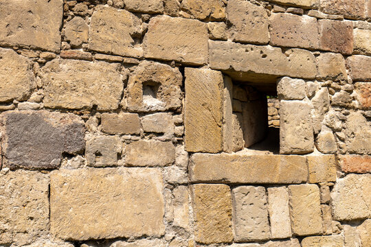 Historic stone fortification wall with a small defensive loophole in Eisenstadt, Burgenland, Austria. Close-up of old masonry and military architecture.
