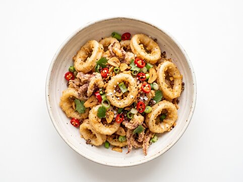 Crispy fried calamari rings in a bowl with chili peppers and herbs squid
