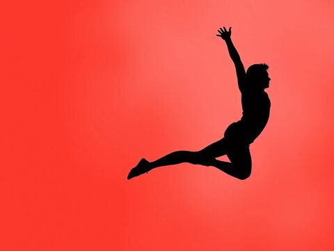 Silhouette of an athlete in mid-air, arm extended, and leg flexed, action, dynamic