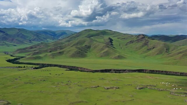 Aerial view of the Orkhon Valley Natural and Historical Reserve with rolling green hills, a winding river, and traditional gers in Xarxorin, Ovorkhangai, Mongolia.