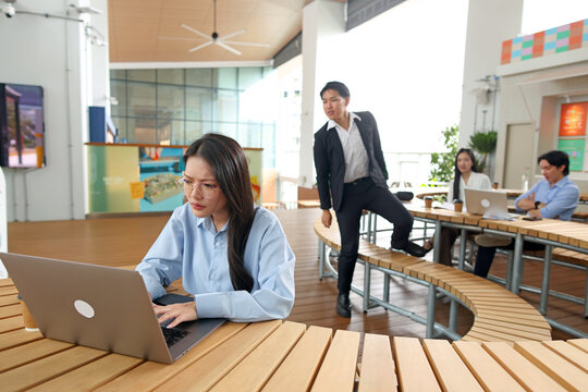 Focused Young Businesswoman Working on Laptop in Modern Outdoor Office Space