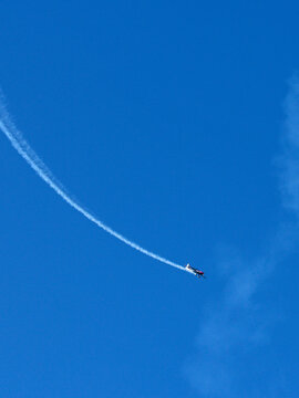 Stunt Plane Performing Aerobatics with Smoke Trail in Blue Sky