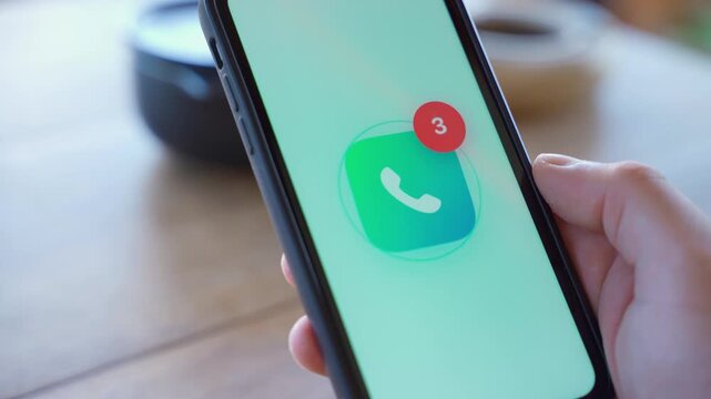 Hand holding smartphone with missed calls appearing on screen close-up