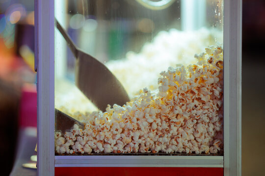 Fresh Crunchy Popcorn Inside A Vintage Machine At Amusement Park. Close-up of delicious warm popcorn filling a commercial maker display glass case