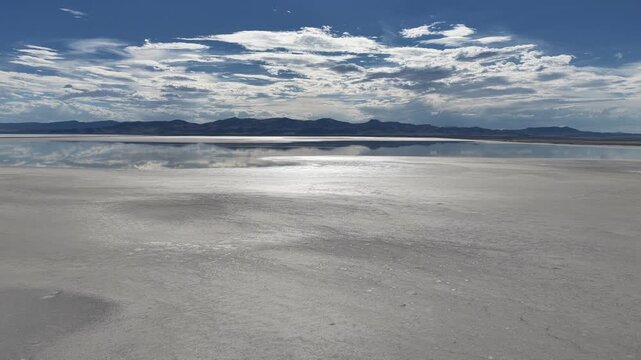 Aerial view of the Great Salt Lake with its expansive salt flats reflecting the dramatic cloudy sky and distant mountains in Salt Lake City, Utah, United States.