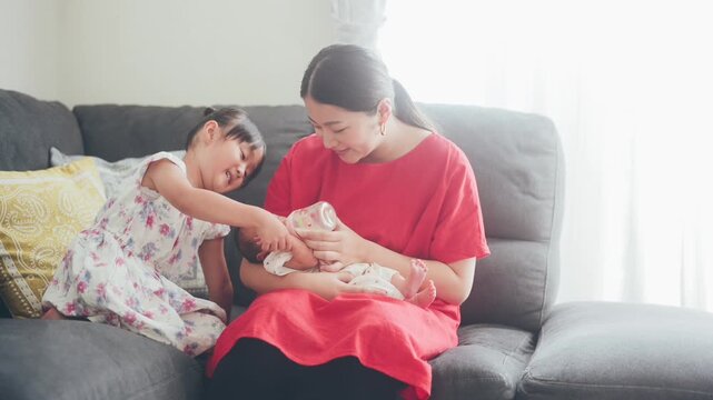 赤ちゃんのミルクをあげるお母さんんとお姉ちゃん