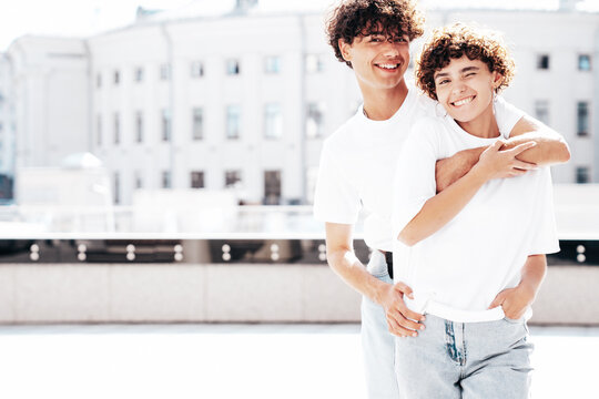 Young smiling beautiful woman and her handsome boyfriend in casual summer white t-shirt and jeans clothes. Happy cheerful family. Female having fun. Couple posing in street at sunny day