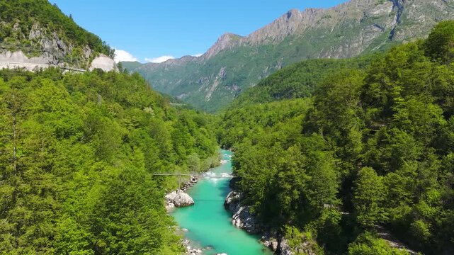 Aerial view of turquoise Soca river winding through lush green forest valley in Julian Alps Slovenia.