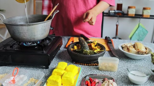 Homechef pouring cooking oil into hot pot on gas stove for cooking indonesian chiken curry