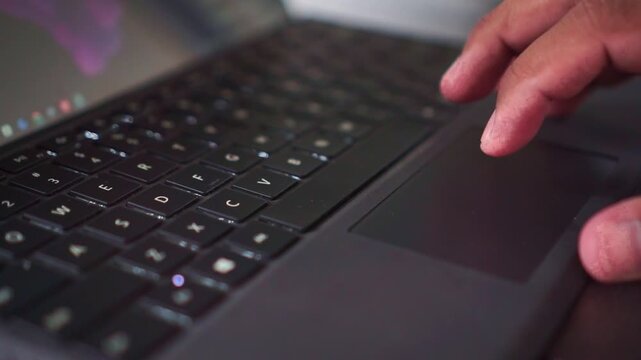 Close up of human hand using laptop trackpad and typing on keyboard in high quality video.