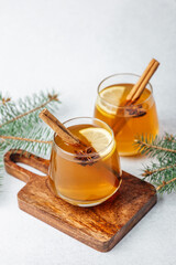 Warm apple cider with cinnamon and star anise in glass mugs on a wooden board © reddish