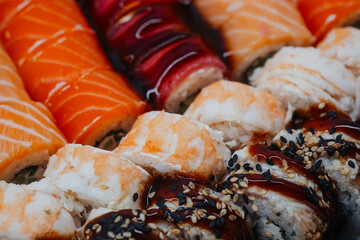 Assortment of fresh sushi rolls with salmon and shrimp in a dark background © reddish