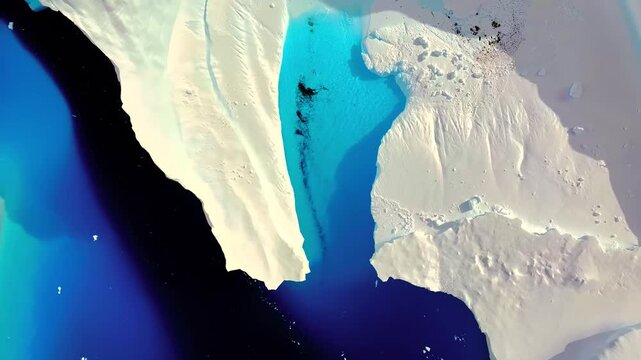 Aerial drone perspective of vast iceberg crack drifting in deep blue Antarctic ocean waters high view.