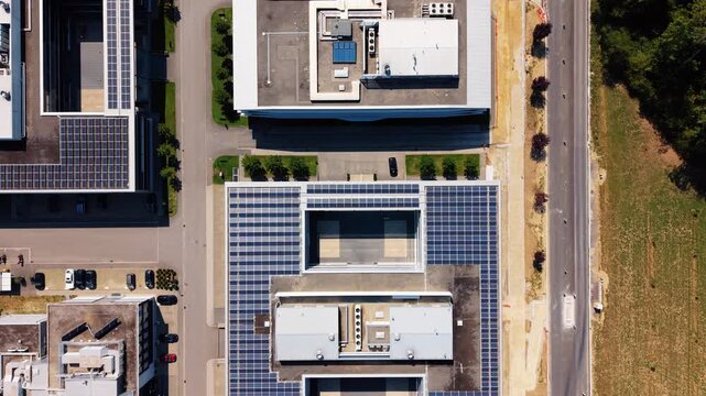 Aerial view of the building at Rte de Crassier 11 featuring extensive rooftop solar panels, surrounding parking areas, and nearby roads in Eysins, Vaud, Switzerland.