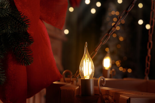 Warm glowing chandelier bulb with festive Christmas decorations and bokeh lights