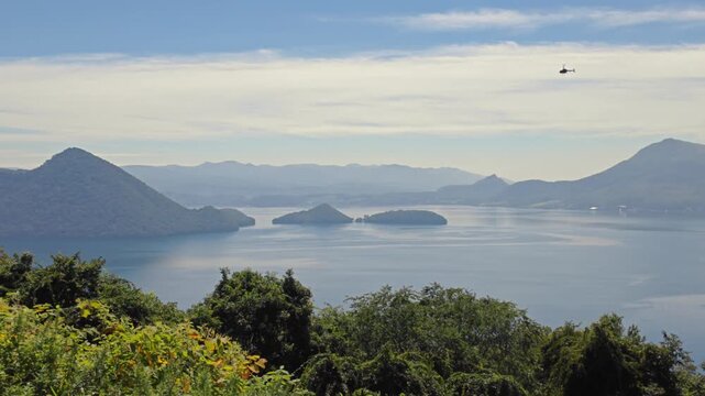 上空をヘリコプターが通過する湖の風景。