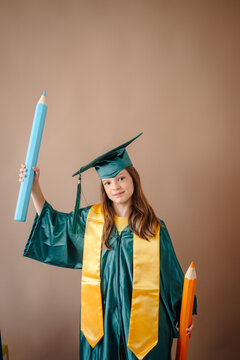 Young student celebrating graduation with giant pencils