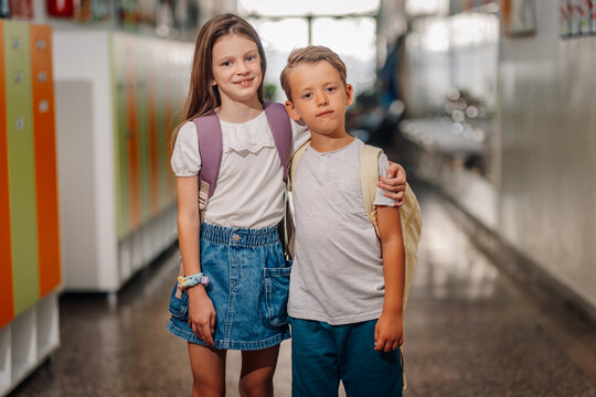 Young students standing in school hallway with backpacks