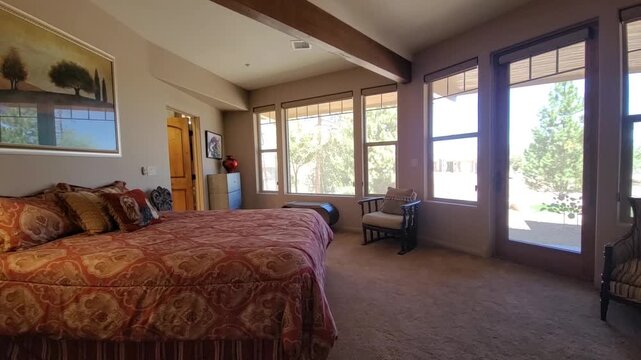 Bright hotel-style bedroom with large bed and windows