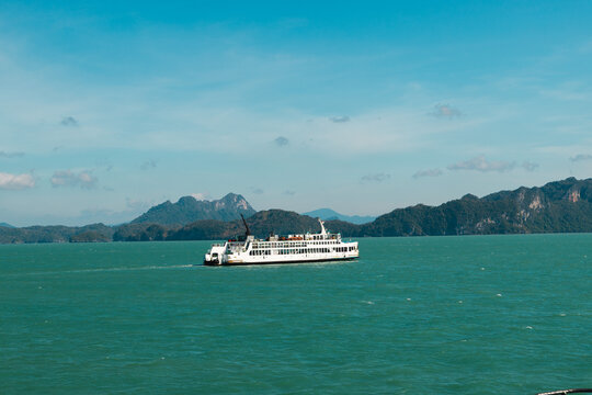 Passenger Ferry Crossing Turquoise Sea Beneath Mountainous Coastline
