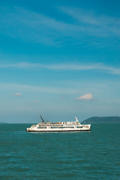 White Passenger Ferry Crossing Turquoise Sea Near Forested Island