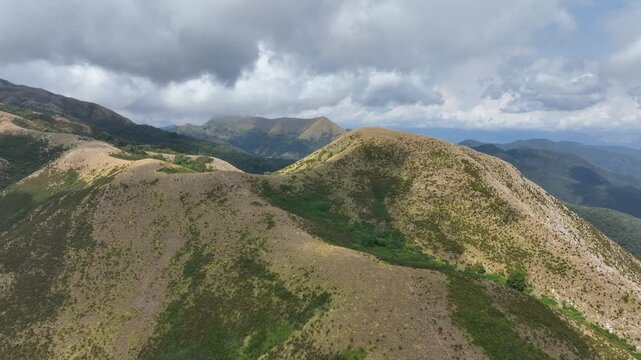 Aerial view of Monte Prana with rolling green hills and cloudy sky in Camaiore, Toscana, Italy.