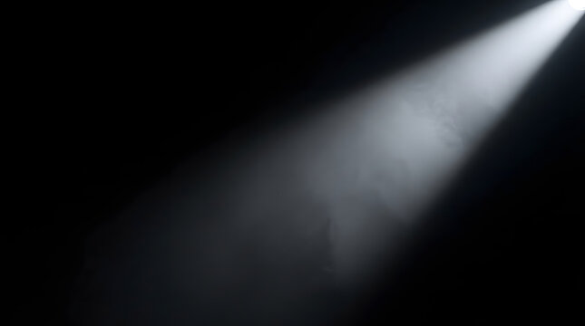 A bright white spotlight beam shining through dark misty air creating a dramatic atmospheric effect on a black background