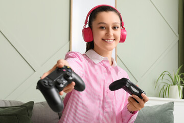 Gaming and entertainment, young woman with headphones holding game controllers for multiplayer video game session at home in living room © Pixel-Shot