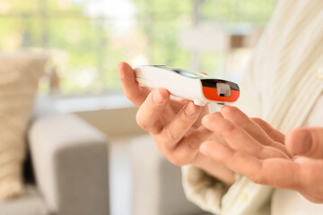 Diabetes management and blood glucose monitoring, person using a digital glucometer to check sugar...