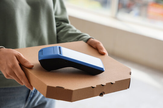 Food delivery payment, courier holding pizza box and mobile card terminal for contactless transaction at customer doorstep for small business service