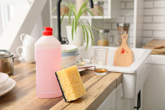 Housework and dishwashing chores, dish soap bottle and sponge on kitchen counter with dirty dishes in sink for home cleaning and hygiene maintenance