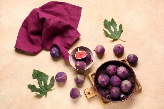 Bowls with fresh ripe figs on beige background