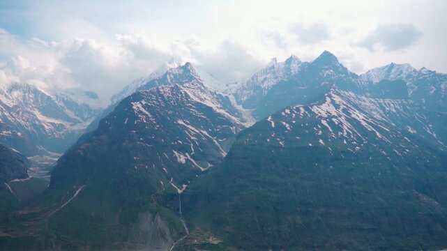 Wide angle shot of snowy Himalayan mountain range with clouds above it during the summer season as seen during the Ghepan Ghat Lake near Sissu in Lahaul and Spiti district, Himachal Pradesh, India.