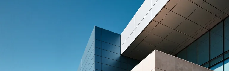 modern minimalist futuristic architecture with blue summer sky, contemporary architectural detail against clear blue sky, sleek geometric building facade in bright sunny daylight © CROCOTHERY