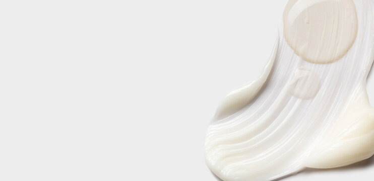 samples of cosmetic care products smear of cream and serum texture on a light background