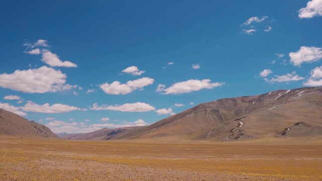 Wide angle shot of clouds above the dry Himalayan mountain range during the summer season as seen from More Plains on Leh Manali highway in Ladakh, India. Scenic natural background with copy space.