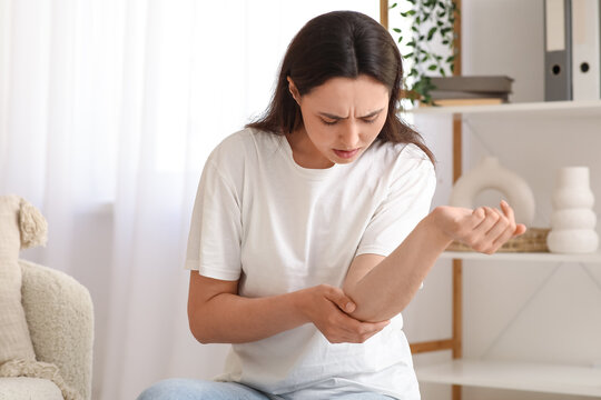 Young woman suffering from pain in elbow at home