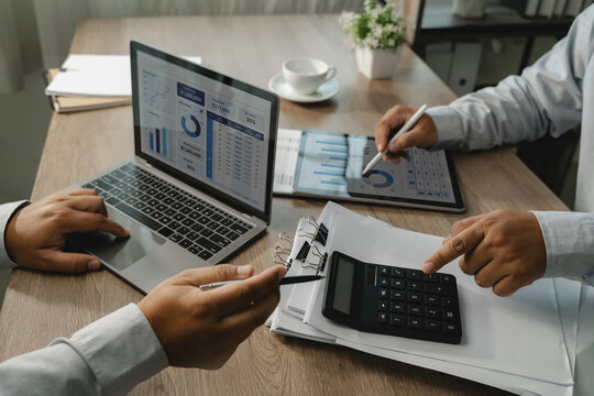 Two businessmen calculating and comparing financial dashboard data on laptop and tablet for accounting analysis, budget review, finance and reporting.
