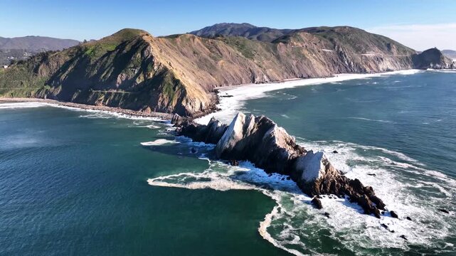Aerial view of Pacific Ocean waves crashing against Devil Slide rock formation in California.