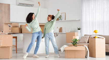 New home excitement and moving day, happy mother and daughter dancing with cardboard boxes in a modern apartment living room and kitchen area