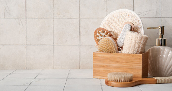 Self care and wellness routine, wooden box with bath accessories and body brushes for spa treatment and skin exfoliation on a tiled bathroom counter