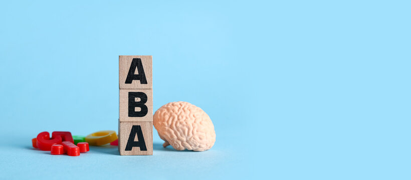 Applied behavior analysis and autism therapy, wooden blocks with aba letters and human brain model for mental health and cognitive development education