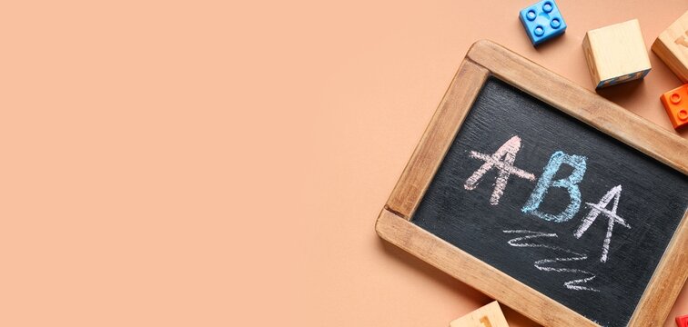 Applied behavior analysis therapy, autism support and child development with chalk writing on a small blackboard and colorful building blocks