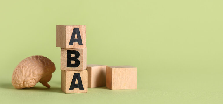 Applied behavior analysis and autism therapy, wooden blocks with aba letters and human brain model for mental health and developmental psychology