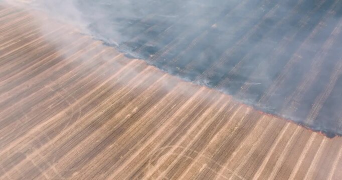Dry farmland fire burning with smoke rising