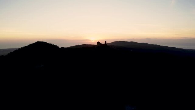 Aerial view of pena palace silhouette at sunset in sintra mountain range.