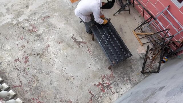 Aerial Drone Shot of Young Metalworker Hammering Welded Metal Sheet